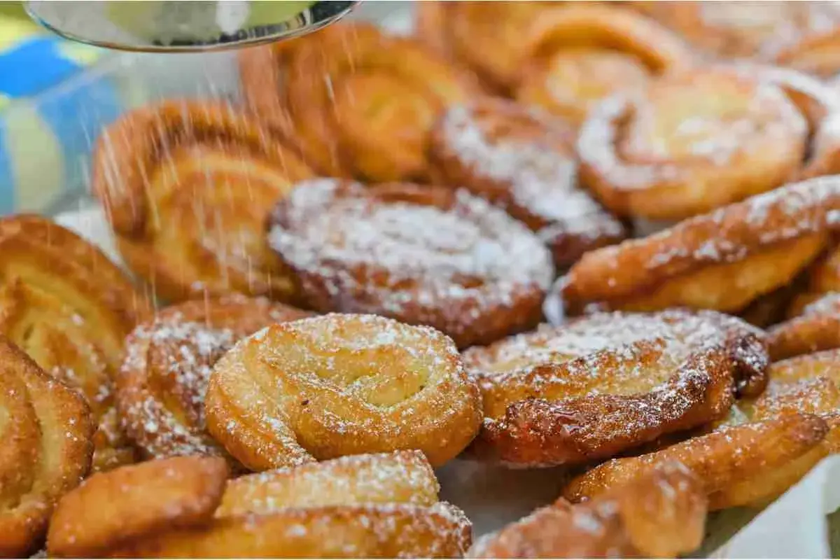 Dolci fritti cosparsi di zucchero a velo, perfetti per il Carnevale. Sembrano deliziosi limoncini, pronti per essere gustati.