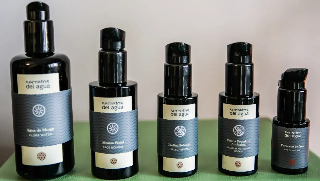 Cinco envases de productos de belleza "Secretos del Agua": agua de musgo, mousse facial, peeling selectivo, crema antiaging y contorno de ojos.