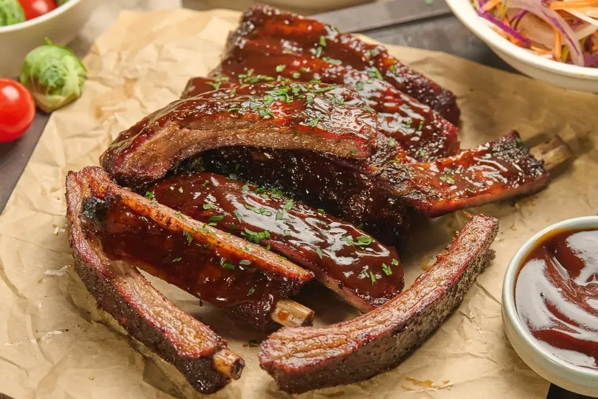 Délicieuses ribs partie du porc, nappées de sauce barbecue et parsemées de persil frais. Un délice à savourer !