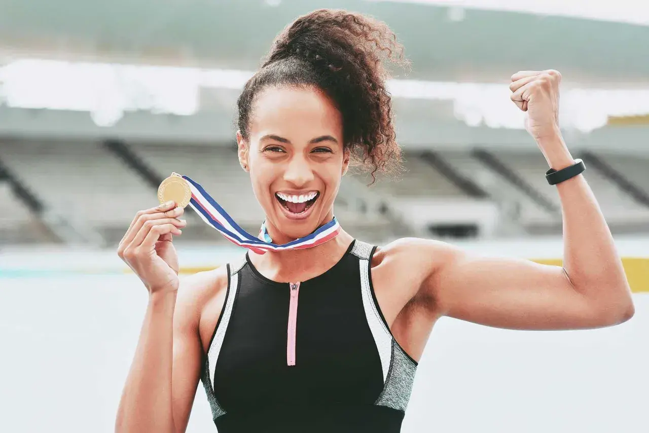 Atleta felice con medaglia d'oro dopo la corsa 10 km. Celebra la vittoria con un pugno alzato.
