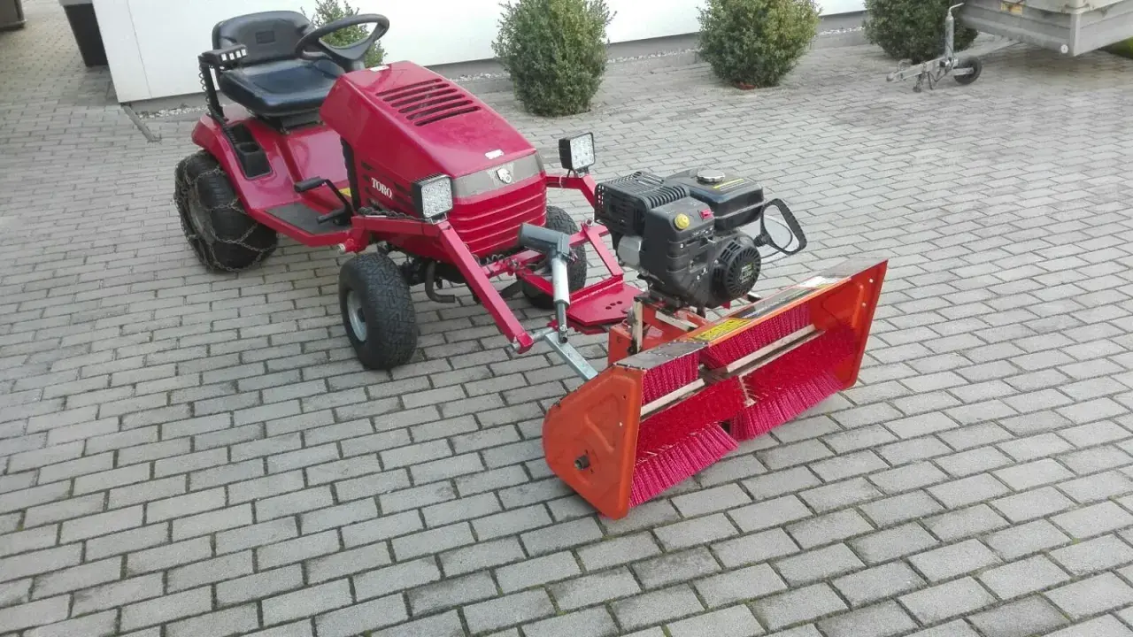 Selbstgebaute Kehrmaschine mit Toro-Aufsitzmäher, Motor und breiter Bürste. Perfekt für den Winterdienst!
