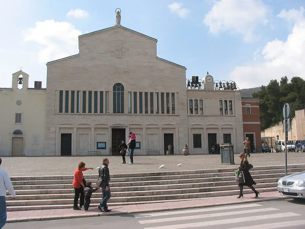 San Giovanni Rotondo: jak zaplanować pielgrzymkę śladami Ojca Pio. Plac przed bazyliką, ludzie wchodzą po schodach.