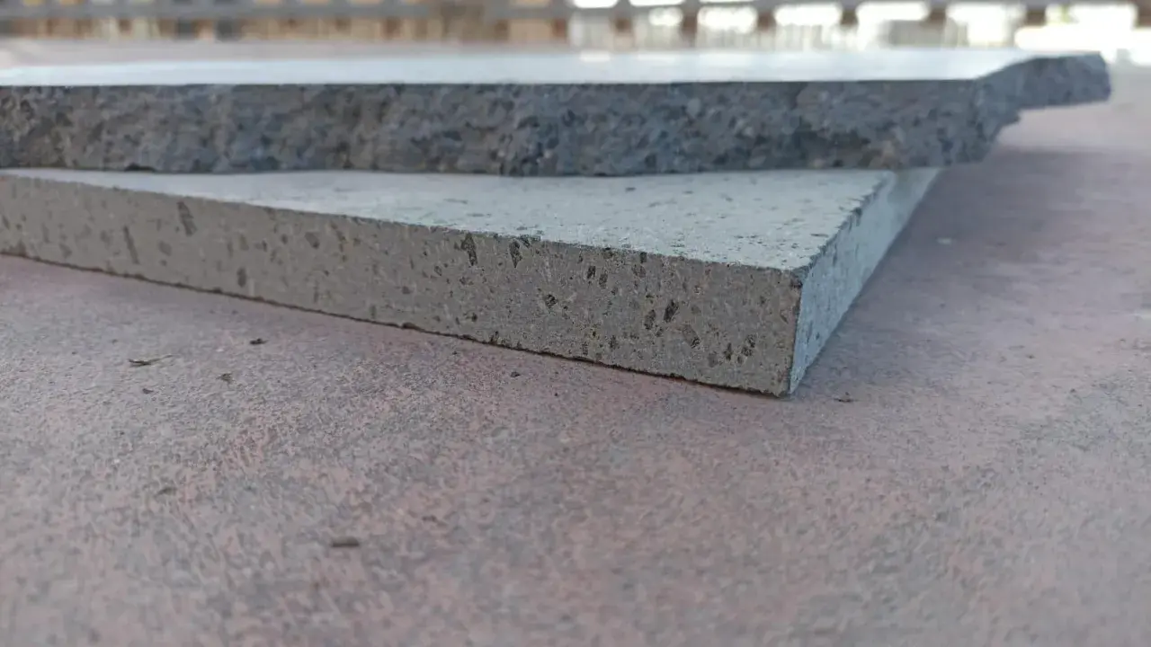 Due piastrelle in pietra lavica, una più chiara e porosa, l'altra più scura e compatta, mostrano la loro texture unica.