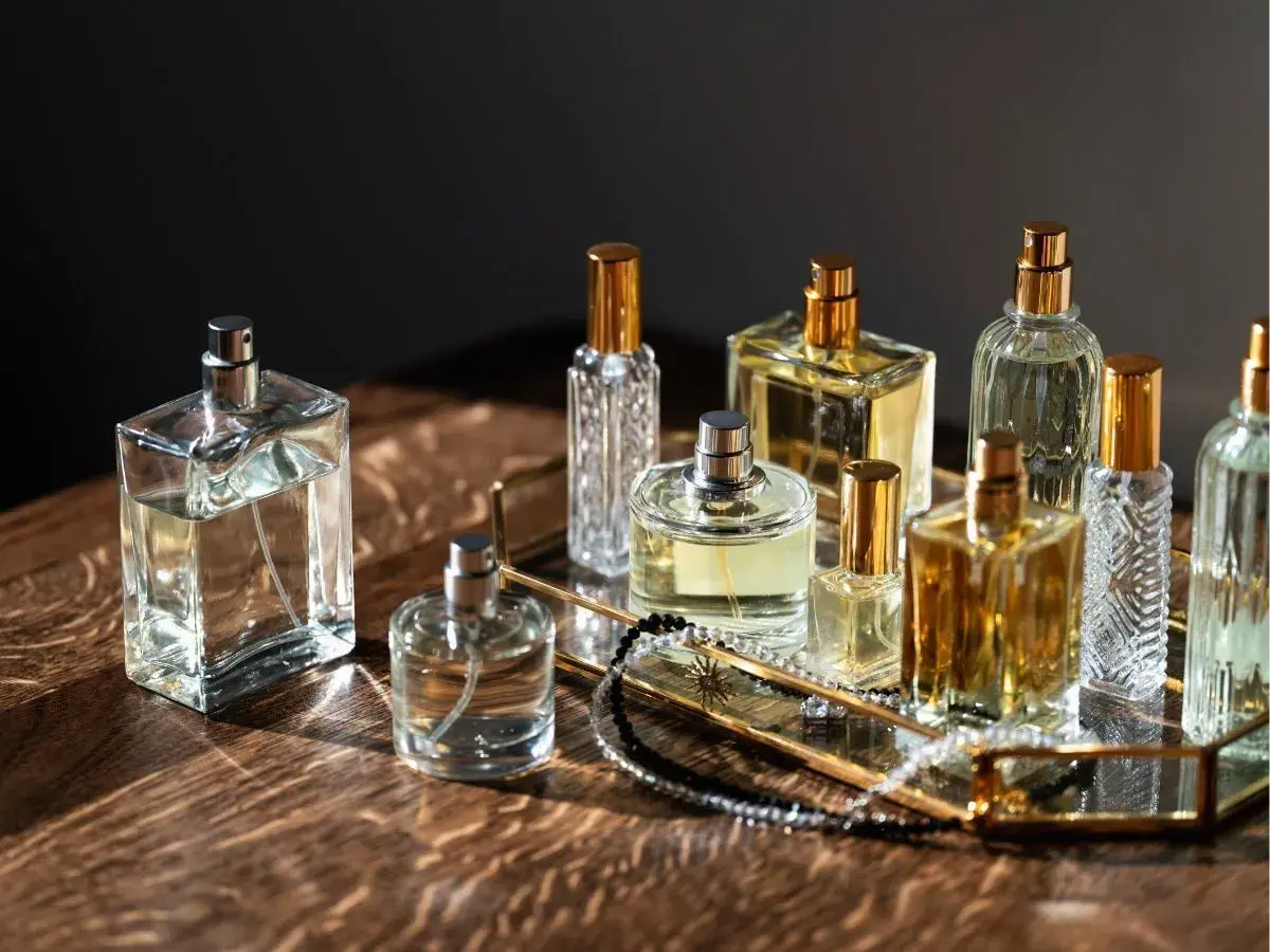 Kolekcja flakonów perfum, w tym Estee Lauder Modern Muse, na złotej tacy z biżuterią.