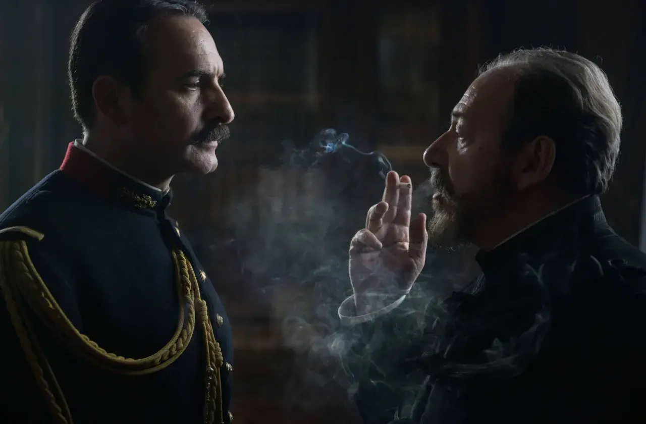 Dwaj mężczyźni w historycznych strojach, jeden w mundurze, drugi z papierosem, w kłębach dymu. Scena z filmu Polańskiego.