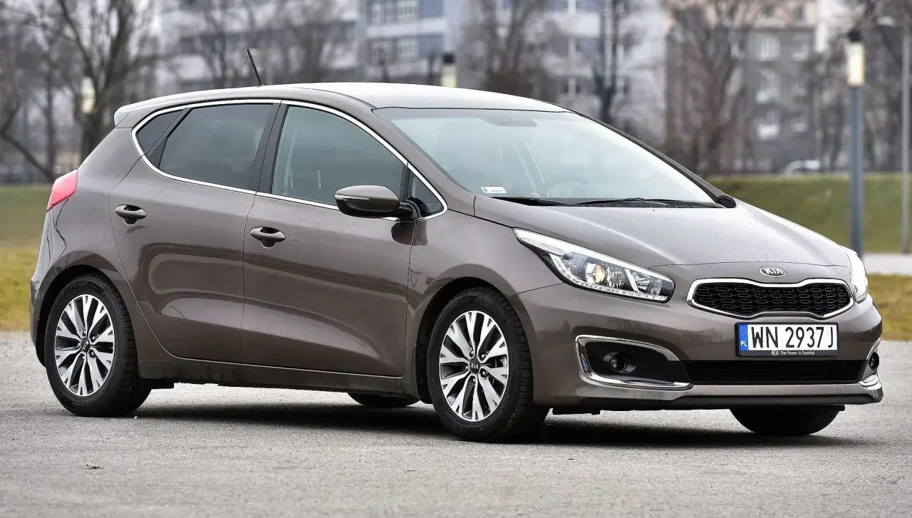 Brązowa Kia Ceed 1.6 benzyna z polskimi tablicami rejestracyjnymi WN 2937J zaparkowana na zewnątrz.