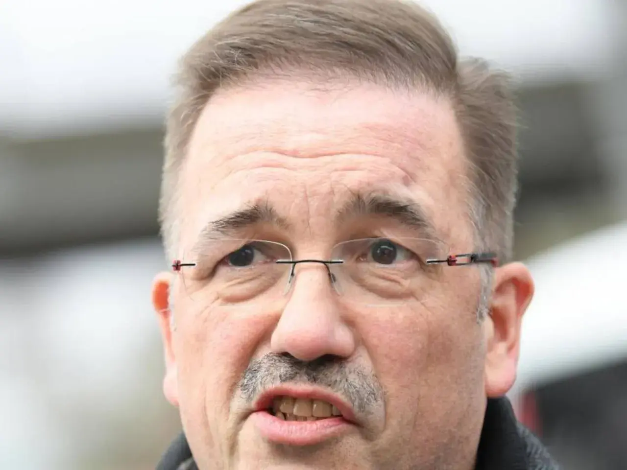 Nahaufnahme von Manfred Wagner mit Brille und Schnurrbart, der nachdenklich in die Kamera blickt.