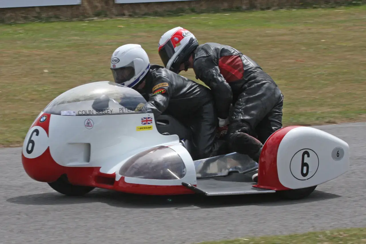 Dos pilotos en un sidecar de carreras, uno conduciendo y el otro en la silla lateral. El número 6 en el sidecar. William Dunlop, un nombre asociado con la velocidad.
