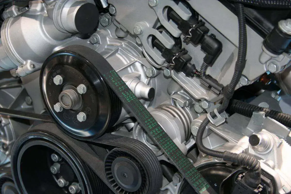 Detalle del motor de un coche, mostrando la polea y la correa de distribución.