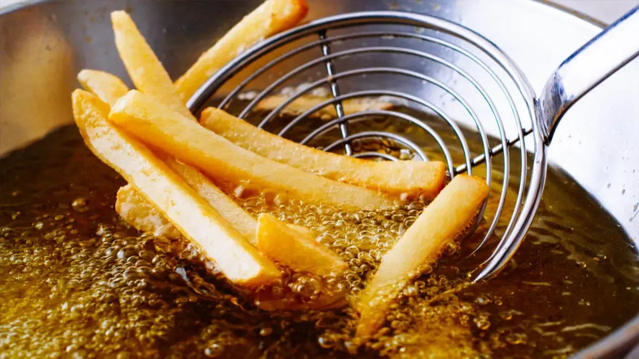 Patatine fritte dorate che sfrigolano nell'olio di oliva, pronte per essere gustate.