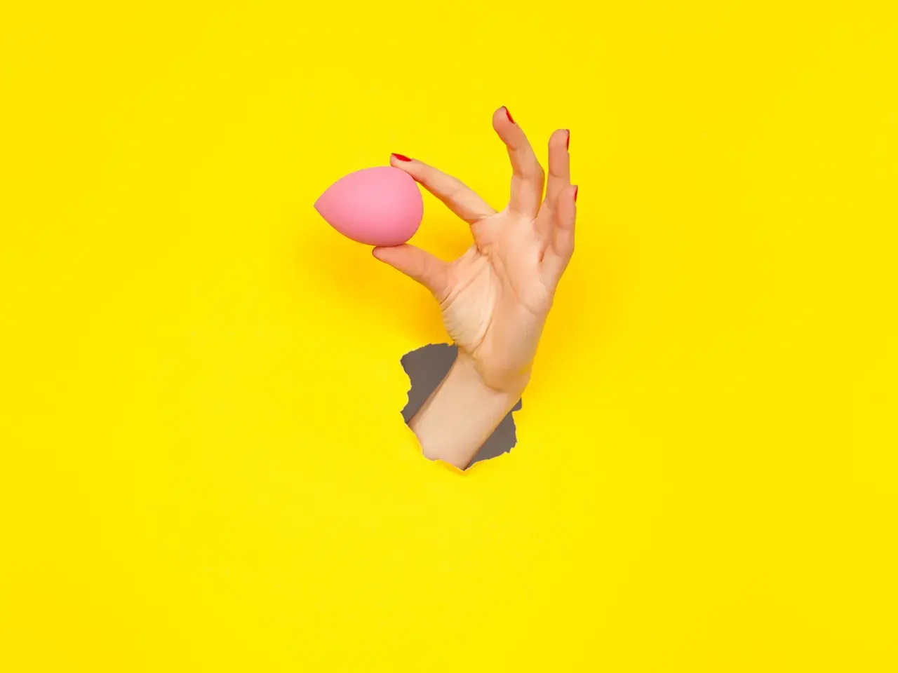 Mano con beauty blender rosa, un modo semplice per capire come pulire le beauty blender.
