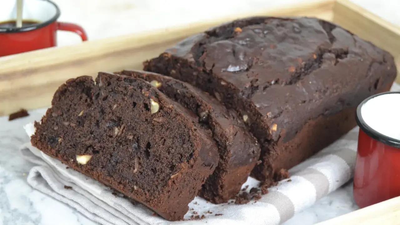 Bizcocho de platano y chocolate, recién horneado y cortado en rebanadas, con trozos de nuez visibles.