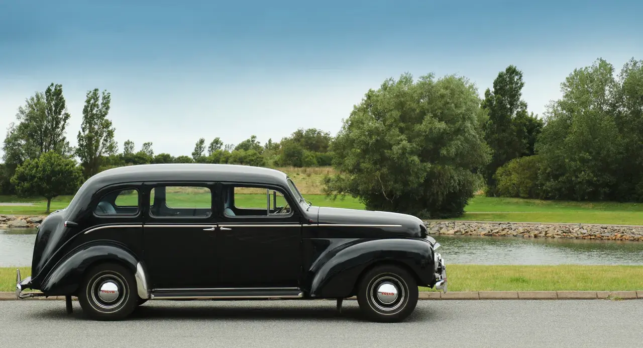 En svart, klassisk Volvo står parkerad vid en sjö. Denna gamla skönhet är en riktig sugga bil, perfekt för en tidlös resa.