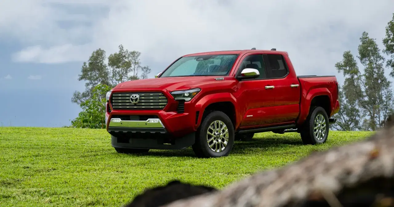 Czerwona Toyota Tacoma na zielonej trawie, gotowa na przygodę.