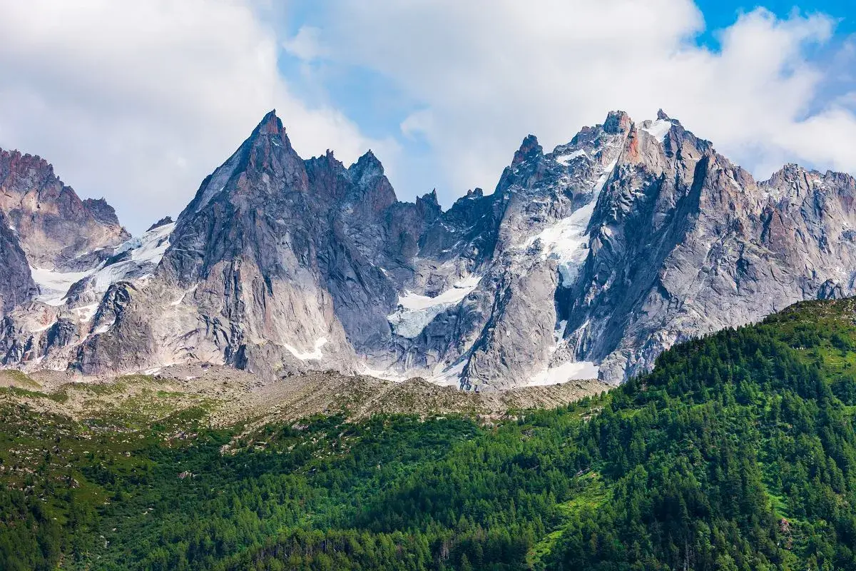 Majestatyczne szczyty Mont Blanc latem, z zielonymi zboczami i resztkami śniegu.