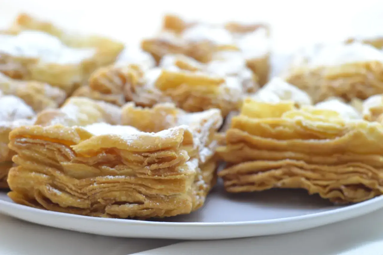 Deliciosos pastelitos de hojaldre con azúcar glas. El hojaldre, con sus capas crujientes y doradas, invita a probarlos.
