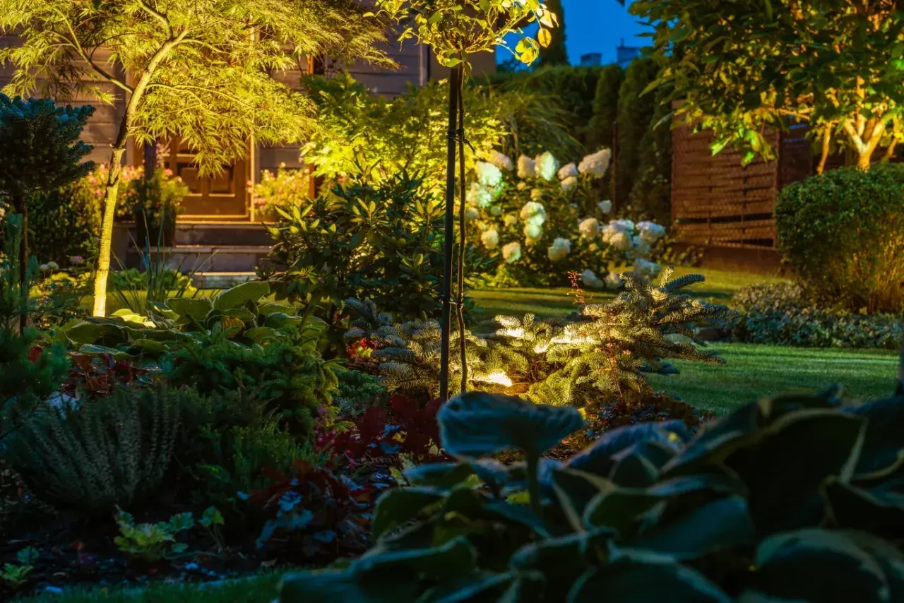Magiczne oświetlenie w ogrodzie aranżacje tworzą przytulną atmosferę. Ciepłe światło podkreśla zieleń roślin i ścieżkę do domu.