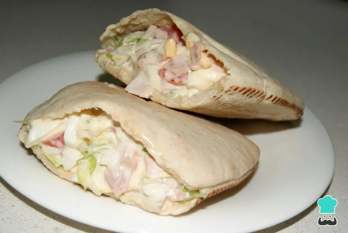 Dos deliciosos bocadillos de pan pita rellenos de ensalada cremosa, jamón y huevo.