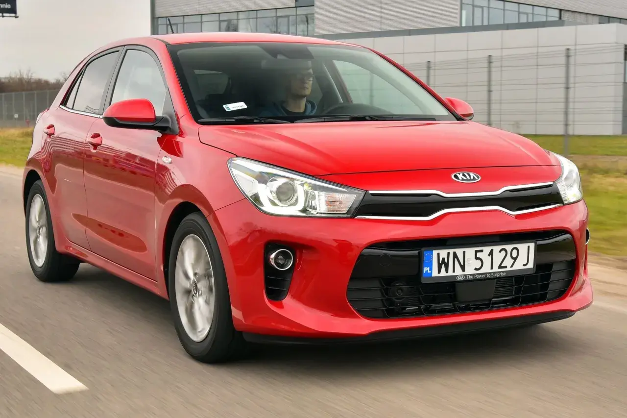 Czerwony Kia Rio 4 w ruchu, z kierowcą za kierownicą.