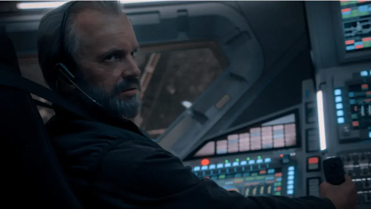 Un homme barbu, casque sur les oreilles, aux commandes d'un vaisseau spatial. L'avenir de l'humanité est en jeu dans For All Mankind saison 5.