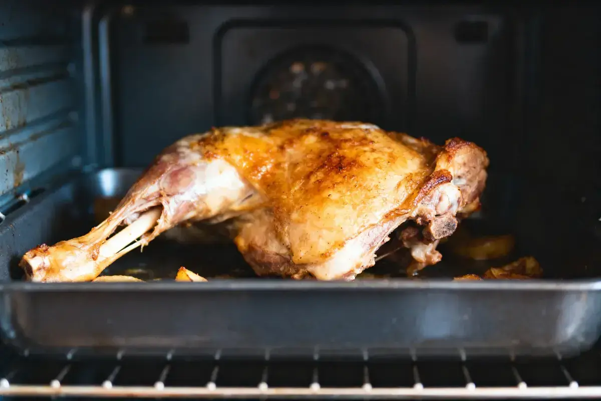 Un gigot d'agneau doré et juteux cuit dans un plat au four, prêt à être dégusté.