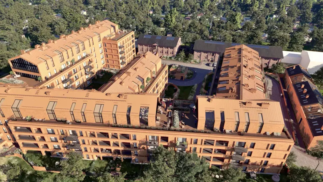 Nowoczesne budynki mieszkalne nawiązujące architekturą do historycznego folwarku Scheiblera. Widać ceglane elewacje, spadziste dachy i zielone dziedzińce.