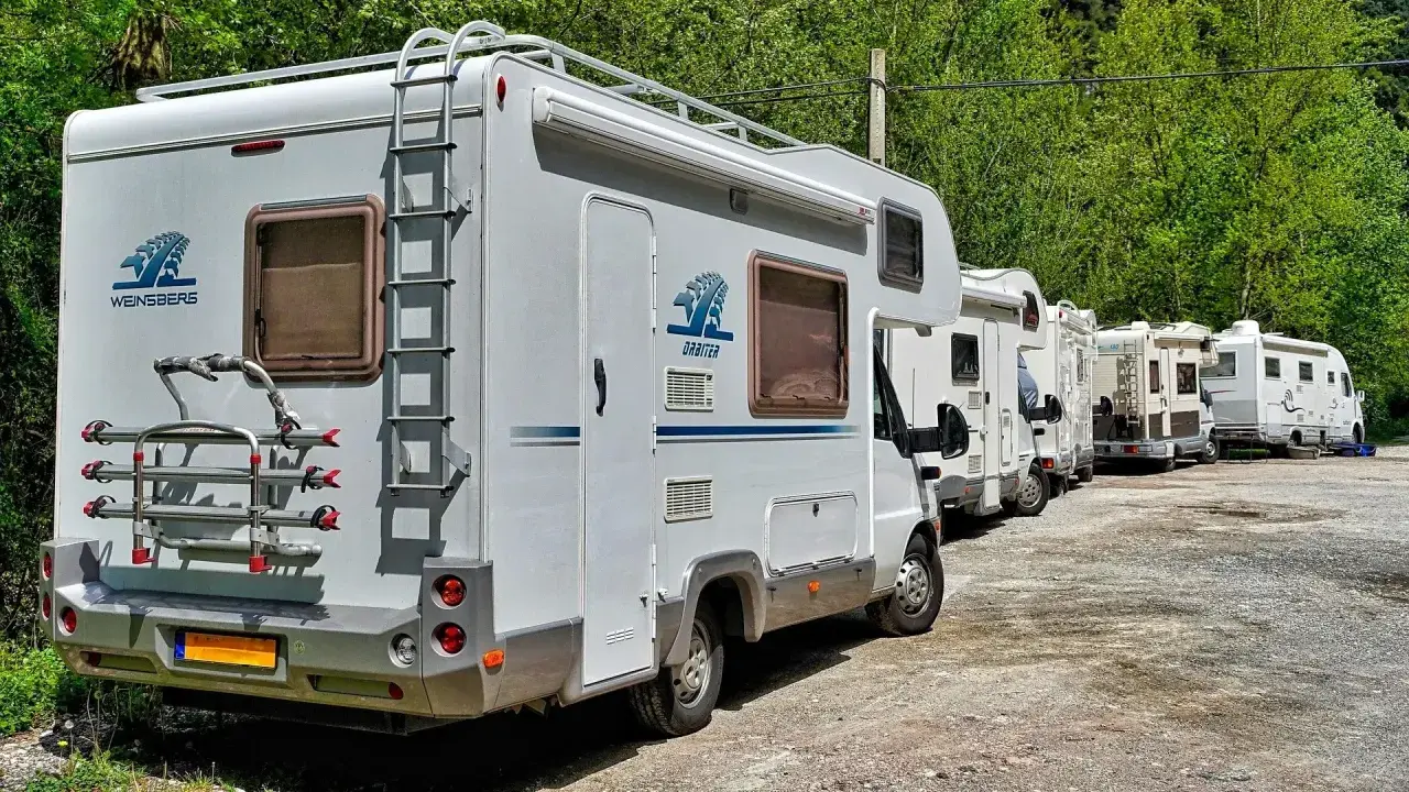 Une file de camping-cars blancs garés dans un paysage verdoyant, prêts pour une aventure à Marseille.