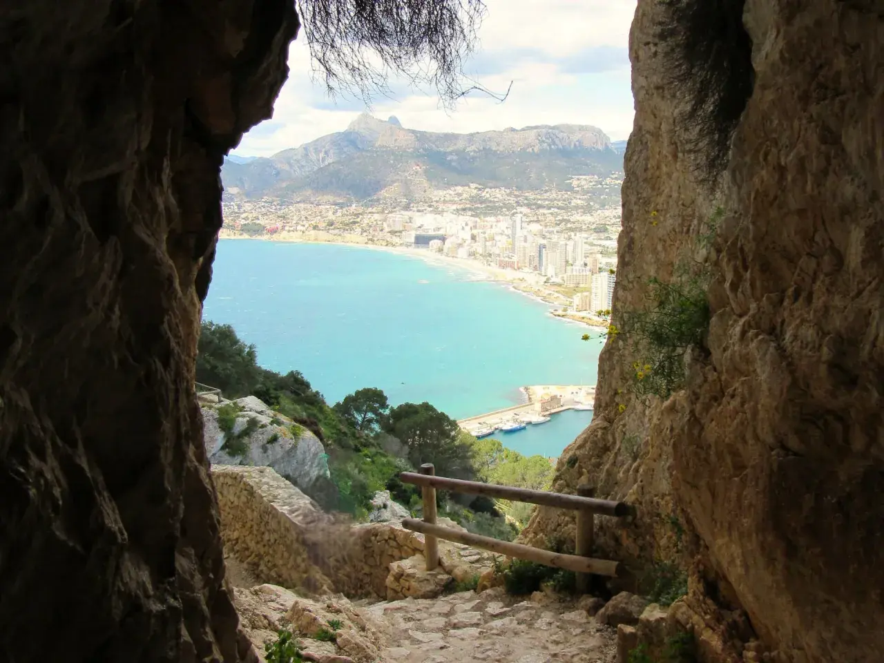 Camino rocoso para subir al Peñón de Ifach, con vistas al mar turquesa y la ciudad.