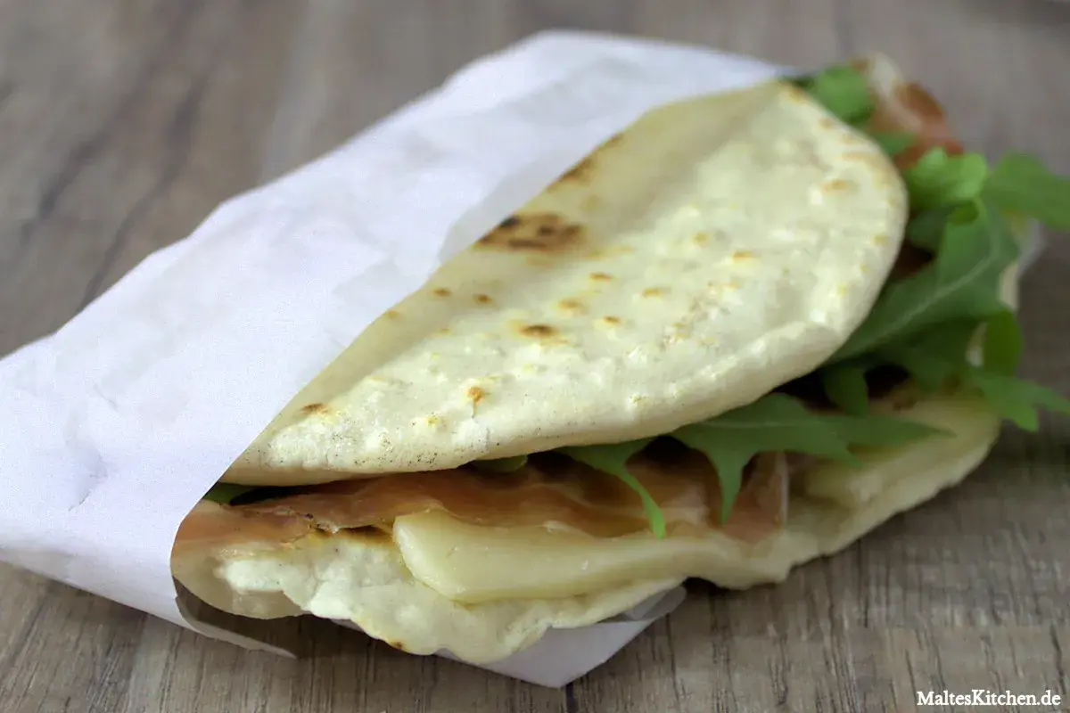 Leckeres Piadina Rezept: Fladenbrot gefüllt mit Schinken, Käse und Rucola, perfekt für unterwegs.