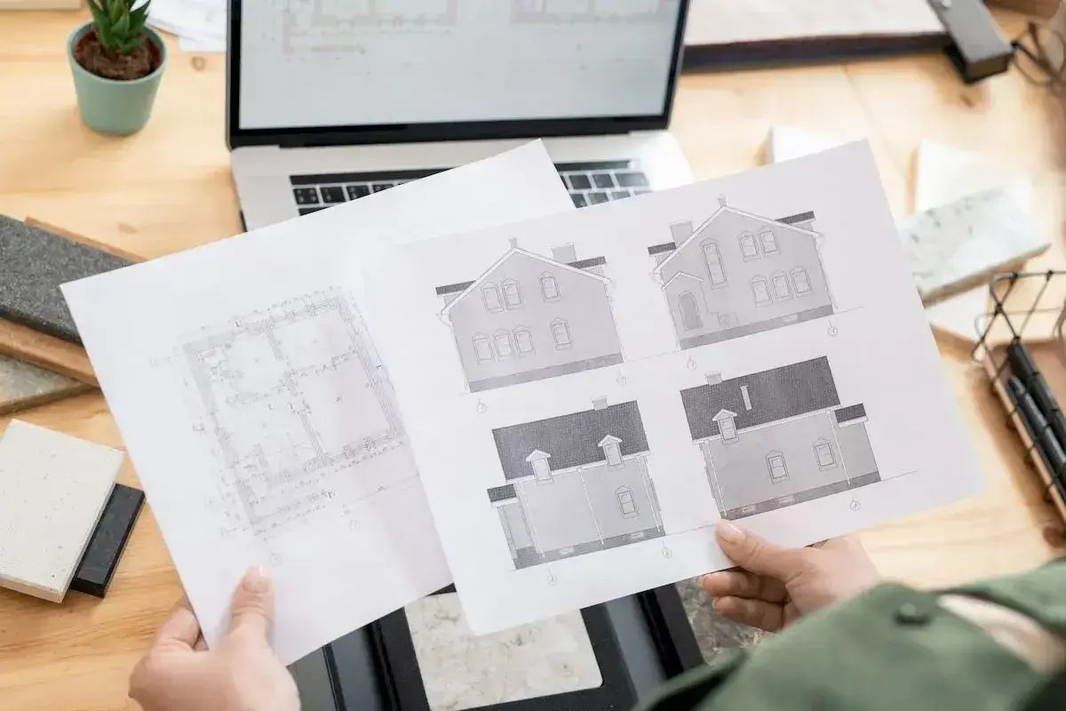 Architekt analizuje plany domu, zastanawiając się, ile trzeba czekać na pozwolenie na budowę.