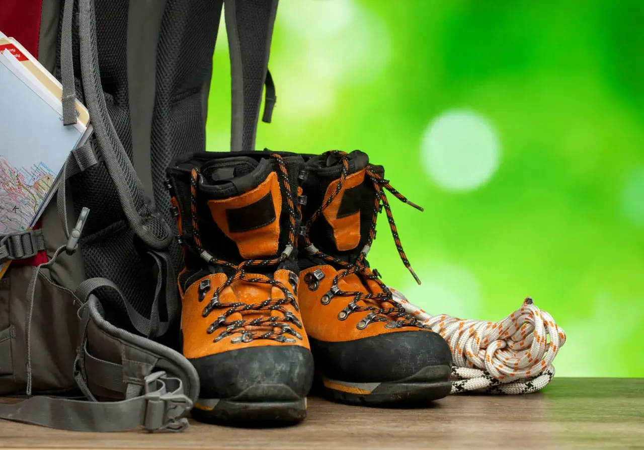 Pomarańczowe buty trekkingowe, plecak i lina. Zadbaj o nie, używając impregnatu do butów z membraną, by były gotowe na każdą wyprawę.