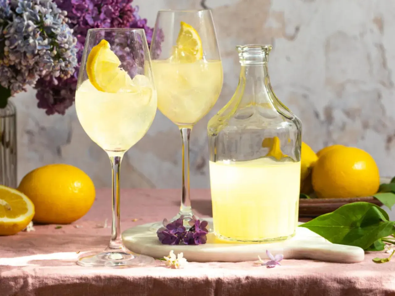Erfrischender Limoncello Spritz mit Zitronenscheiben, Eis und Flieder.