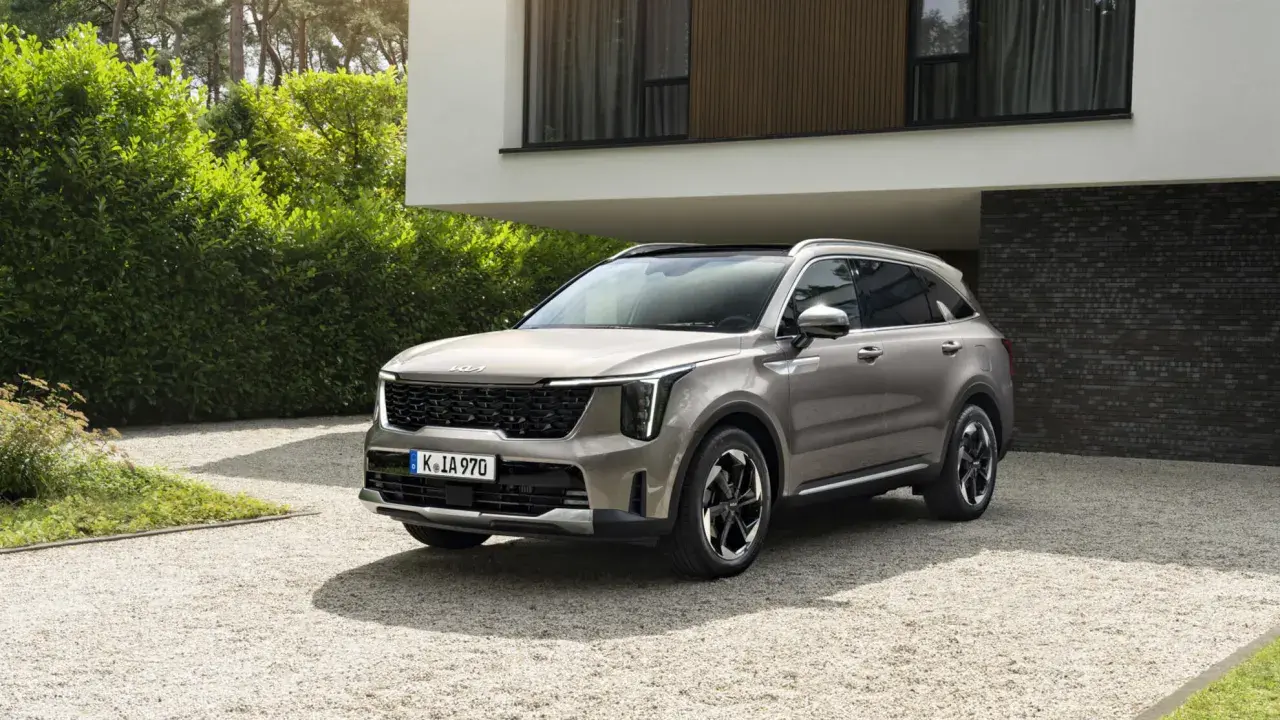 SUV Kia Sorento color sabbia, un esempio delle migliori auto benzina, parcheggiata su ghiaia davanti a una casa moderna.