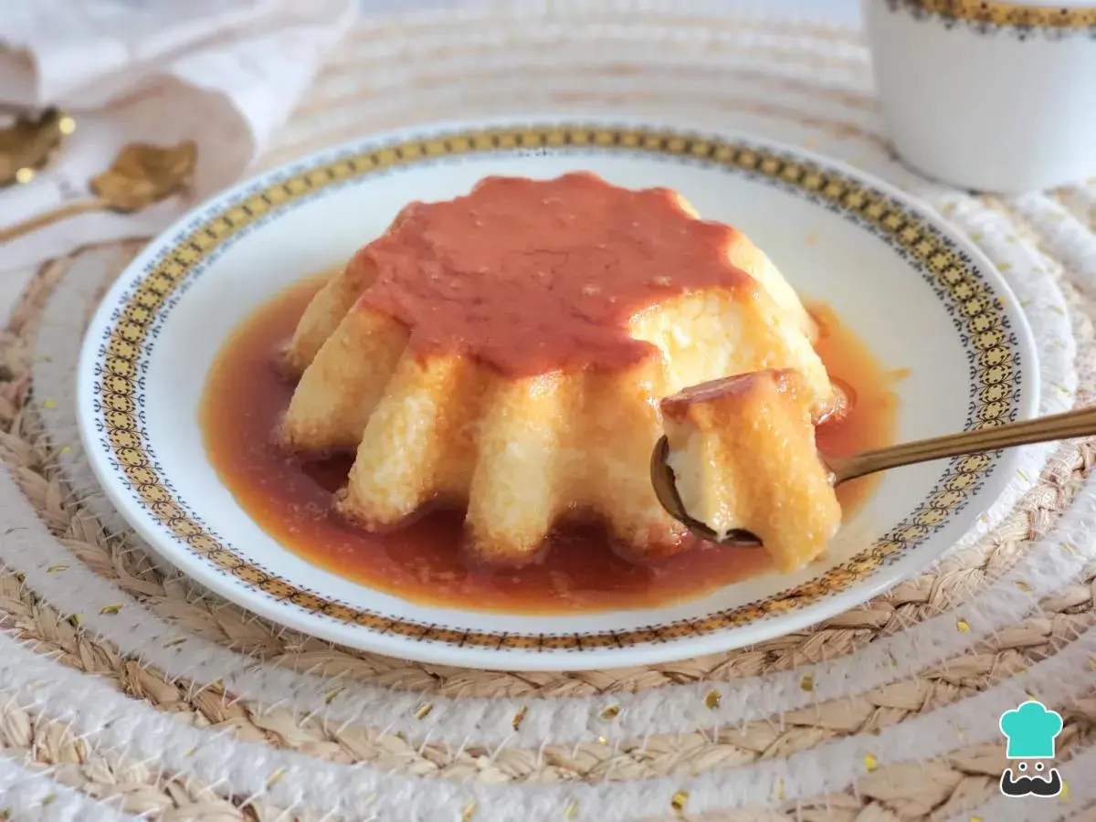 Un delicioso flan casero con caramelo dorado, servido en un plato decorado. Una cucharada revela su textura suave y cremosa.