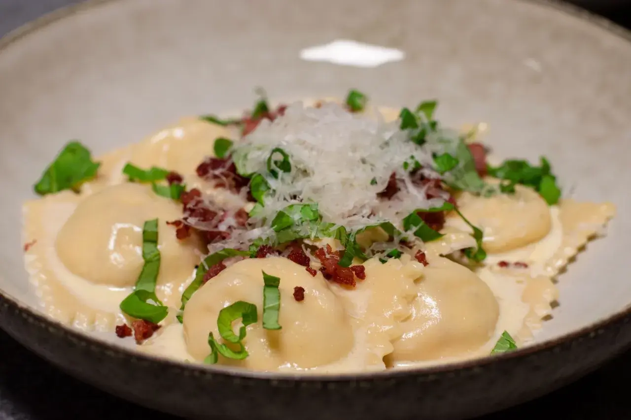 Ravioli salsiccia i krämig sås, toppad med riven parmesan och färska örter. En läcker italiensk rätt.