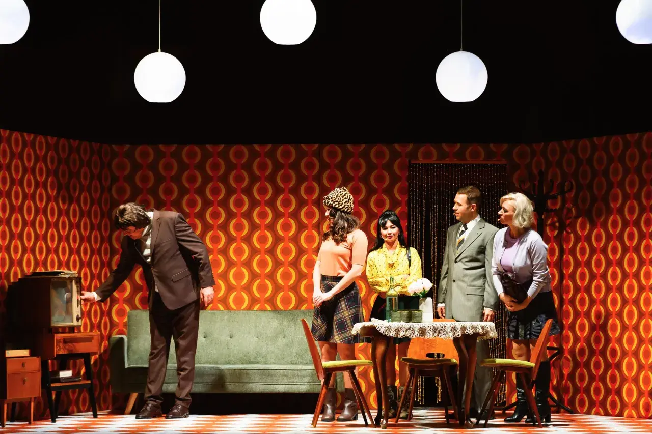 Scena z życia w polskich teatrach: mężczyzna przy starym telewizorze, kobiety w modnych strojach i elegancki pan.