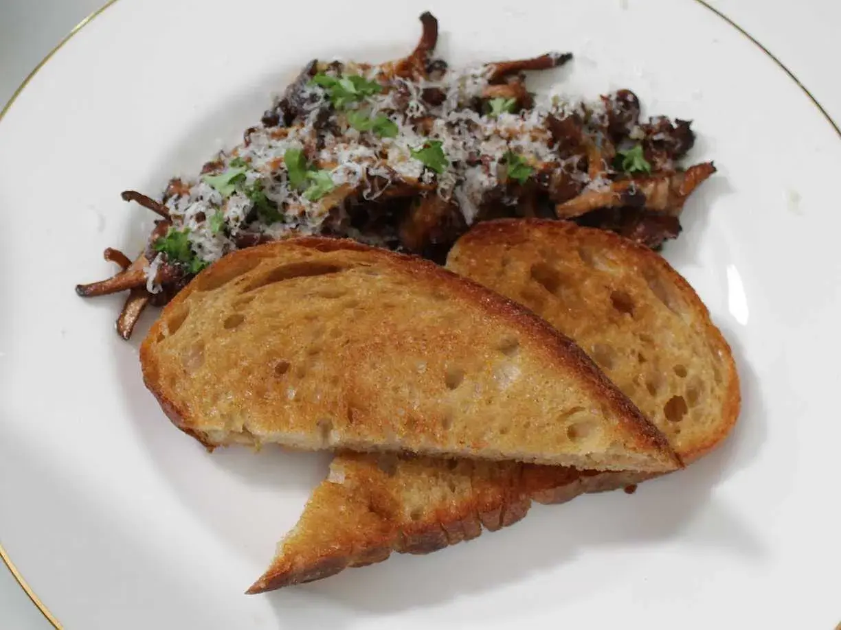 Stekta kantareller med vitlök och persilja, serverade med rostat surdegsbröd. Ett enkelt och gott kantareller recept.