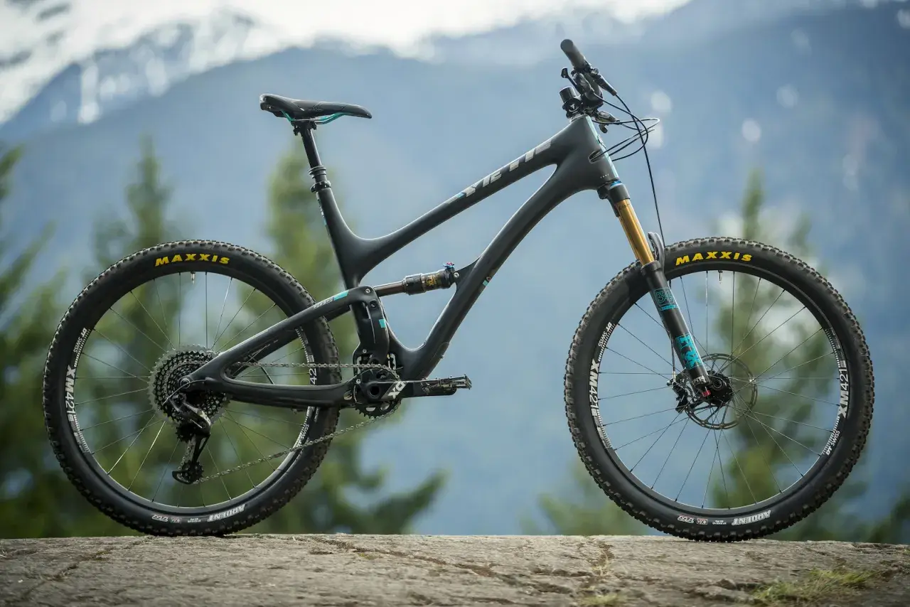 A black Yeti SB5 Turq mountain bike with teal accents sits on a rock, ready for adventure in the mountains.