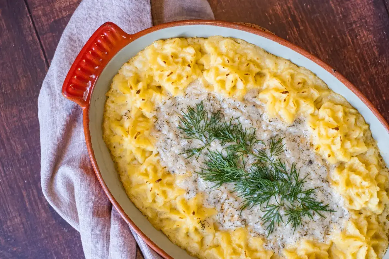 En krämig vegetarisk fisksås med potatismos och dill i en ugnsform.