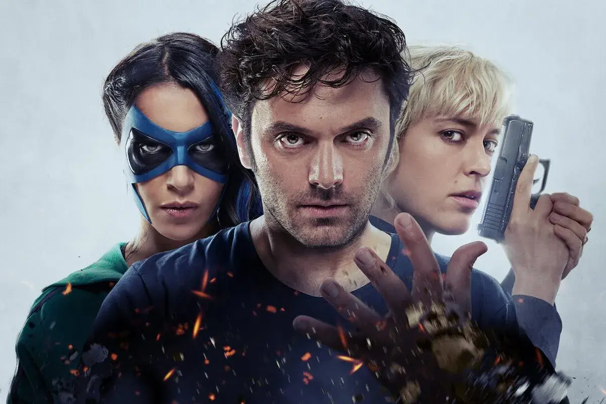 Trois personnages d'un film de super-héros : une femme au masque bleu, un homme au regard intense et une femme blonde tenant un pistolet.