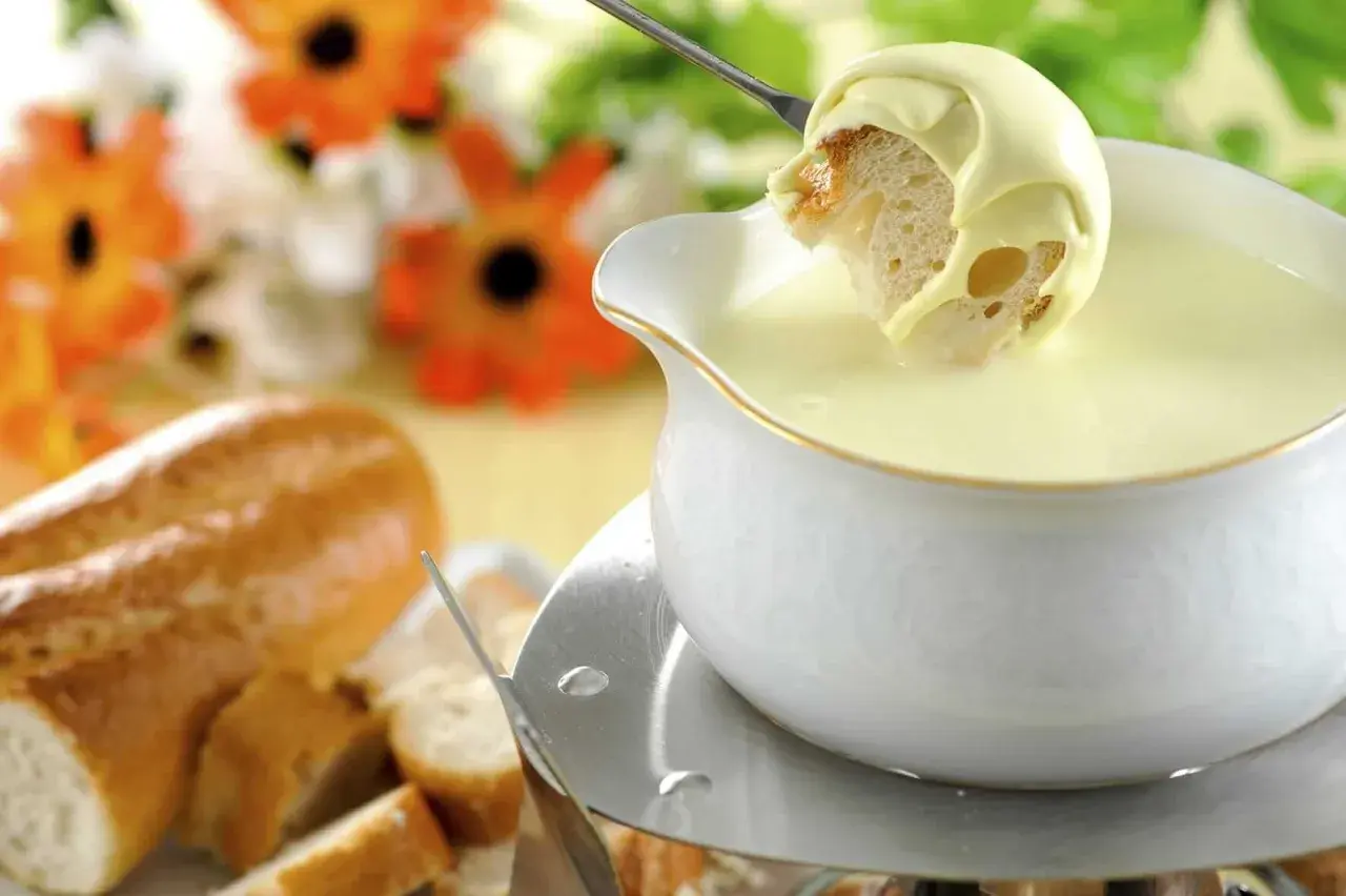 Un pezzo di pane intinto in una fonduta cremosa, un modo delizioso per sciogliere il formaggio.