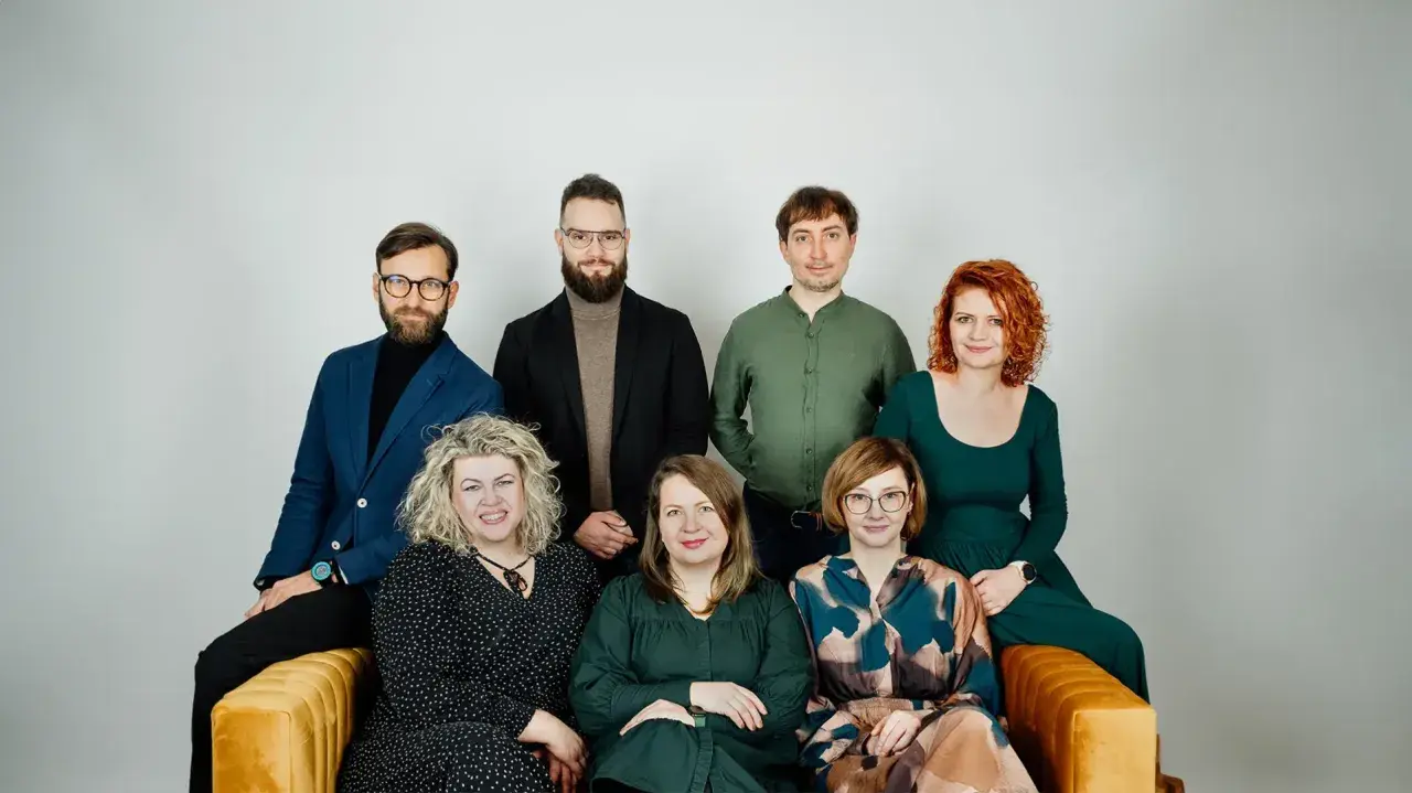 Grupa siedmiu psychoterapeutów, cztery kobiety i trzech mężczyzn, pozuje do zdjęcia na kanapie.