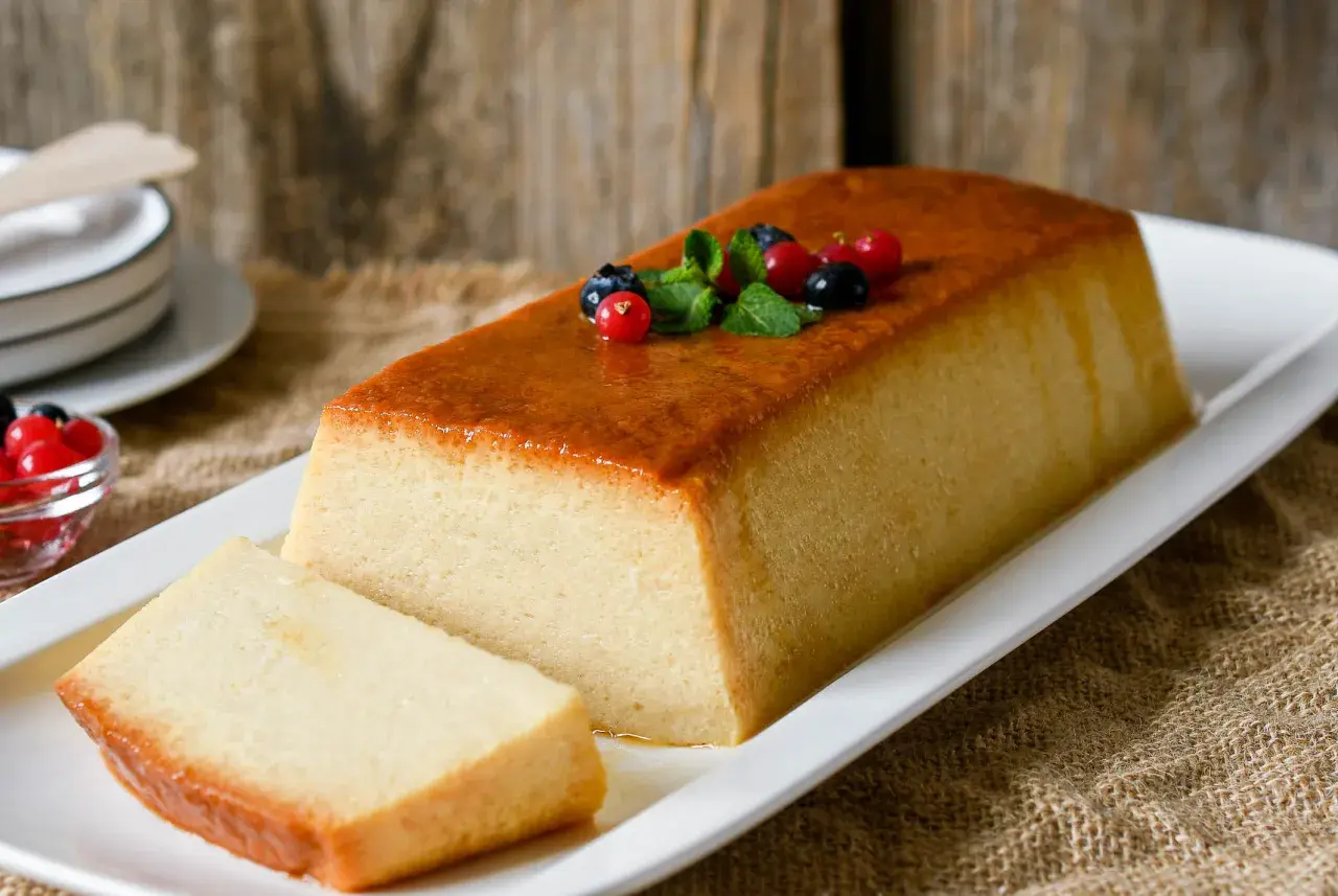 Un delicioso pudin de pan, con una capa dorada y decorado con frutos rojos y menta.