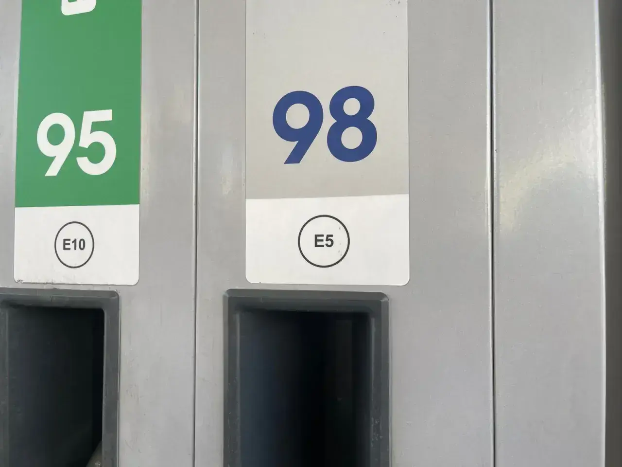 Dwa dystrybutory paliwa: jeden z zielonym oznaczeniem 95 E10, drugi z niebieskim 98 E5.