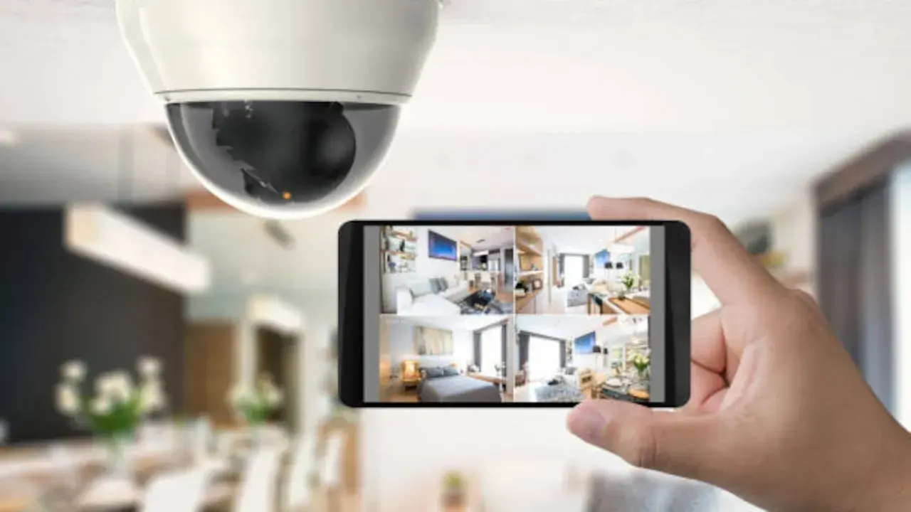 Caméra de surveillance au plafond et smartphone affichant plusieurs flux vidéo, un type d'alarme moderne pour la sécurité domestique.