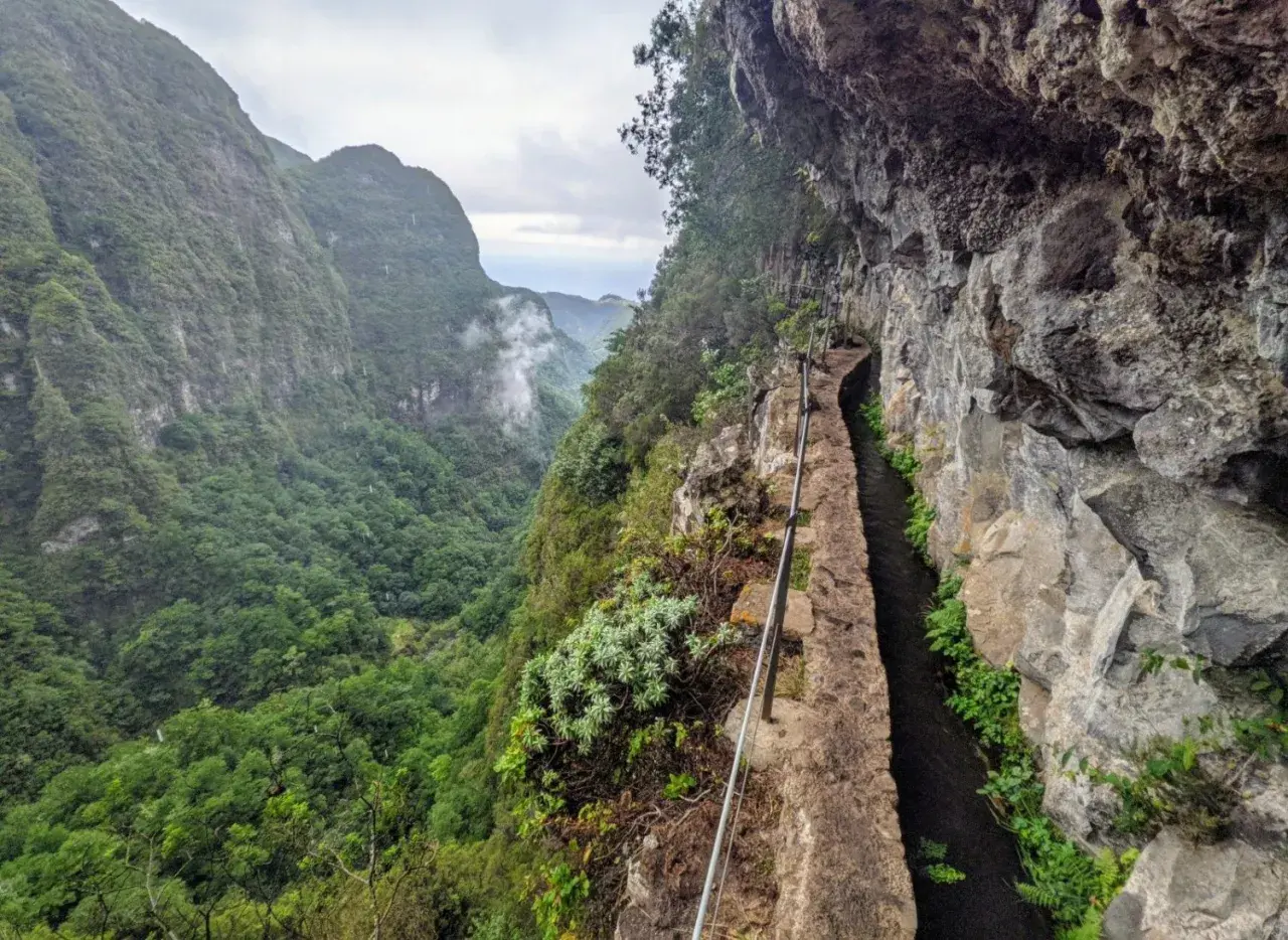 Ein schmaler Weg entlang eines Kanals führt durch eine Schlucht auf Madeira. Die Levadas Madeira sind ein beeindruckendes Wandererlebnis.