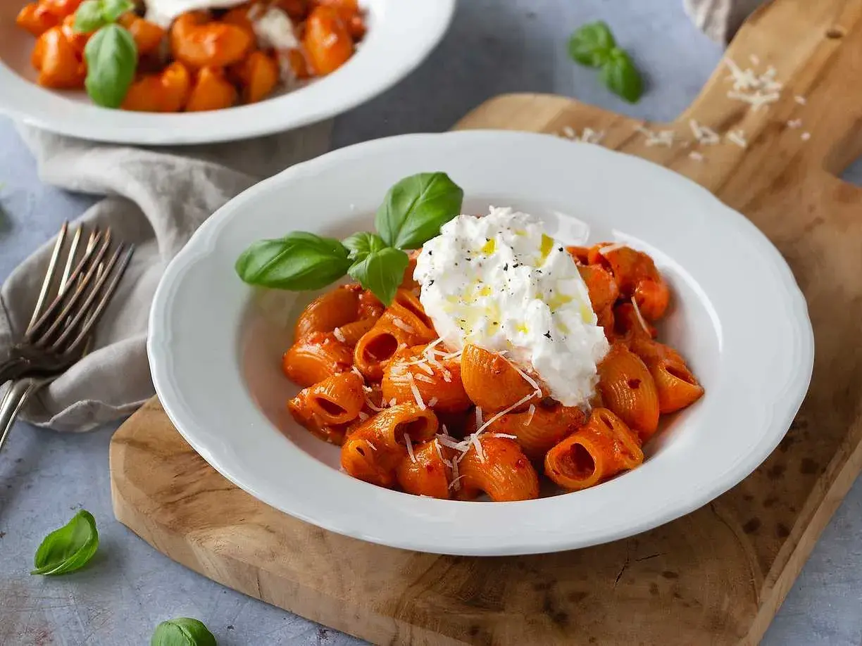 Nduja pasta med krämig burrata, toppad med basilika och olivolja. En härlig italiensk rätt.
