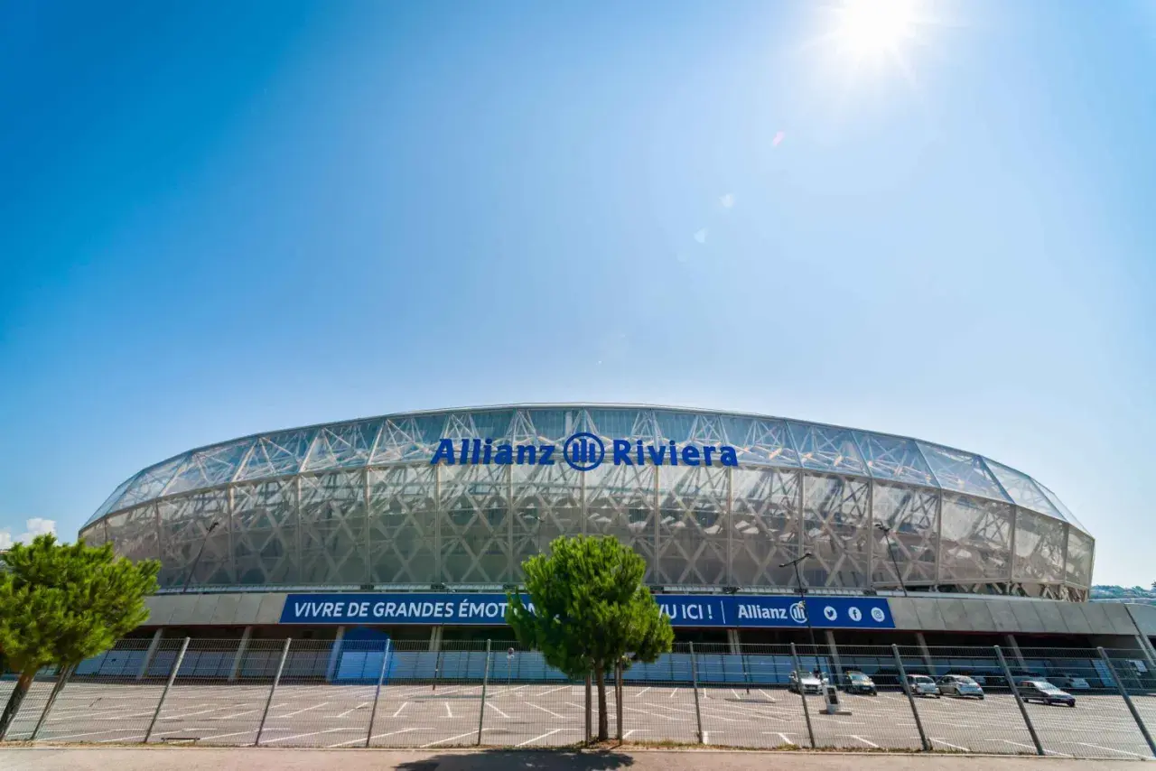 Nowoczesny stadion Allianz Riviera w Nicei, z charakterystycznym, przeszklonym dachem i niebieskim napisem.
