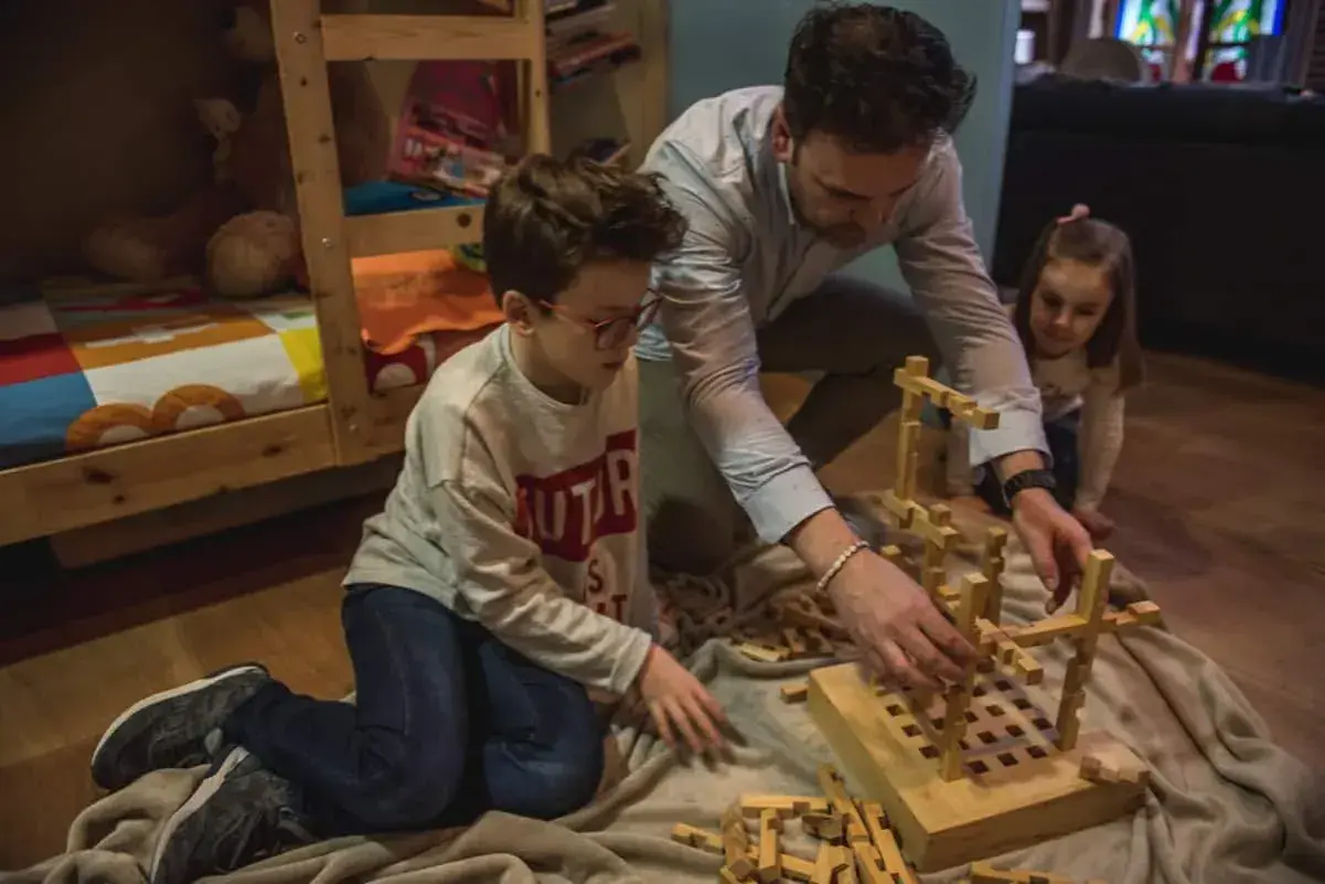 Padre e hijos construyen con bloques de madera, creando sus propios juguetes Waldorf caseros.