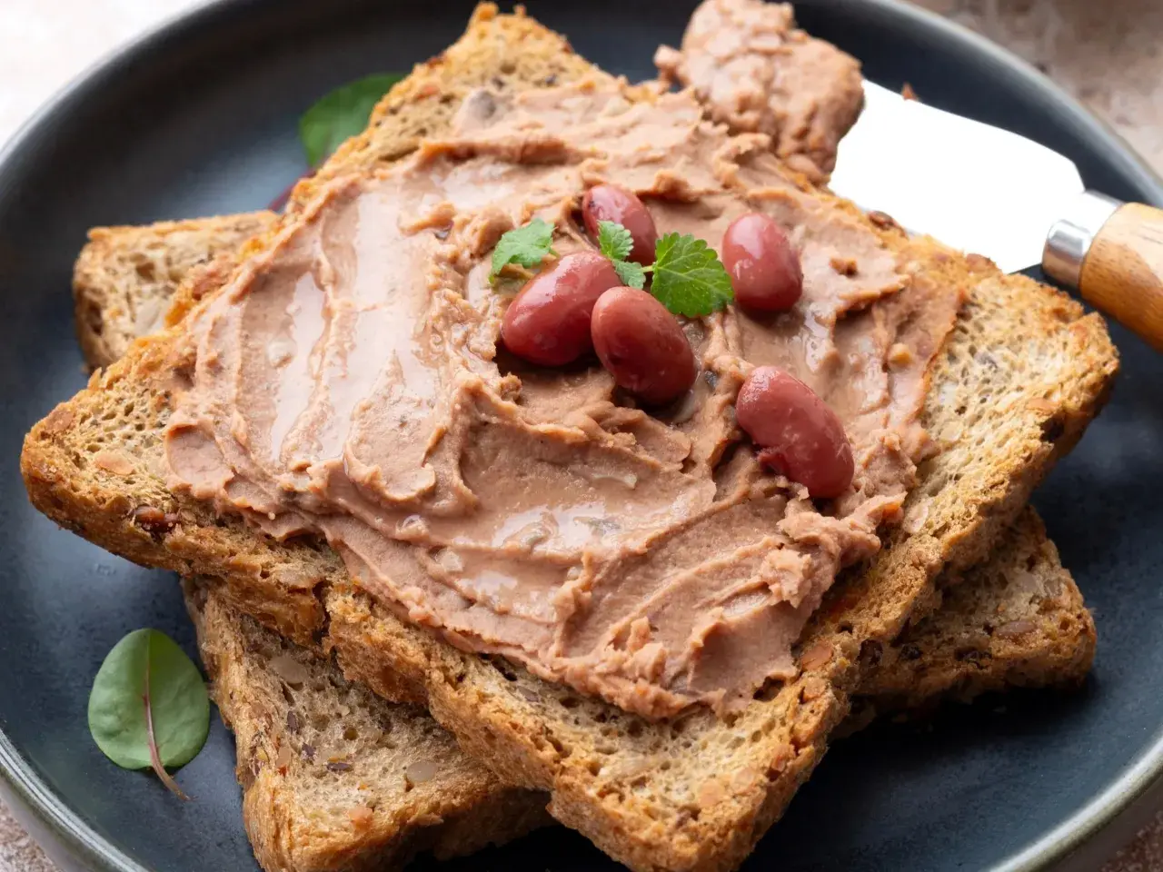 Pyszna pasta z fasoli czerwonej na chrupiących grzankach, ozdobiona fasolkami i listkami ziół. Idealna na szybką przekąskę.